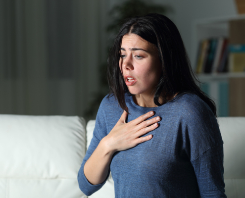 An image of a woman with heartburn holding her chest in pain.